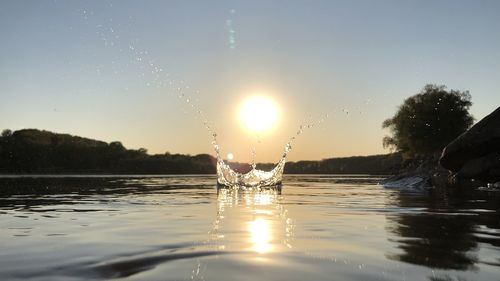 Water splashing in lake against sky during sunset