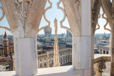 View to spires and statues on roof of duomo through ornate marble fencing. milan, italy