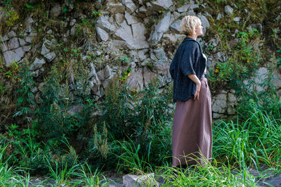 Woman standing on field by wall