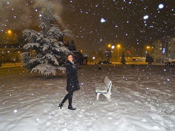 Side view full length of smiling woman on snow covered field at night