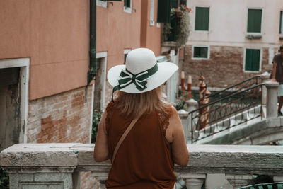 Rear view of woman standing by railing in city