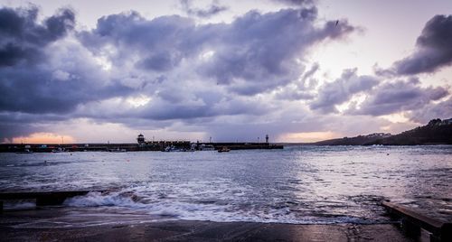 Pier on sea against cloudy sky