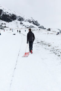 Rear view of person walking on snow covered mountain