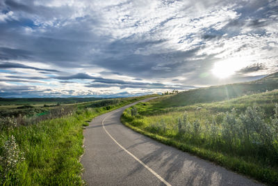 Road amidst field against sky