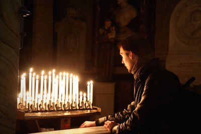 Man looking at lit candles in church