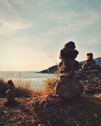 Rocks on beach against sky during sunset