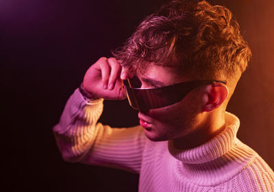 Portrait of young man wearing sunglasses against black background