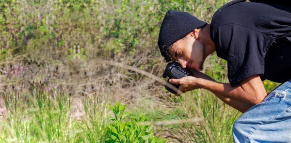 Portrait of a photographer taking pictures of wildlife and plants,  crouched down 