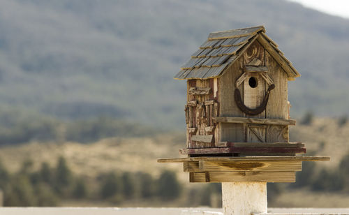 Close-up of wooden birdhouse against mountain