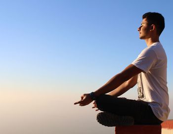 Full length of man doing yoga against sky