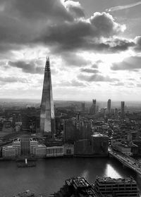 Aerial view of buildings in city against cloudy sky