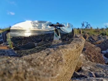 Close-up of ice cream on rock at beach against blue sky