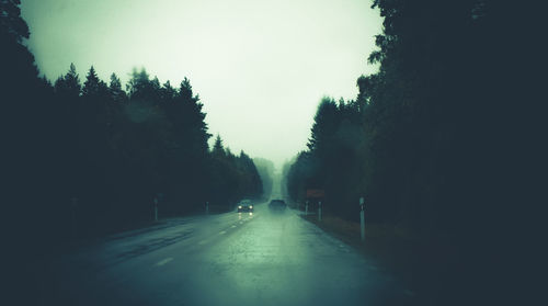 Road amidst trees against clear sky