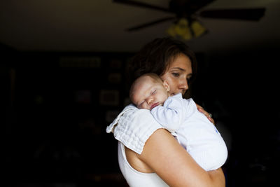 Thoughtful mother carrying baby girl while standing at home