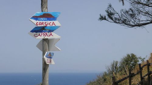 Low angle view of road sign against sea and sky