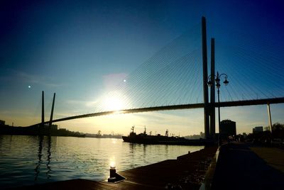 Silhouette bridge over river against sky during sunset