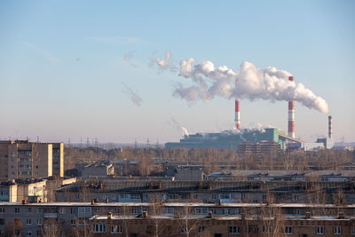 Smoke emitting from factory against sky