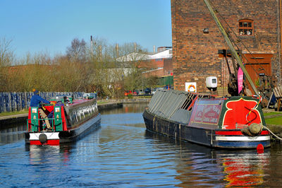 Boats in river against buildings in city