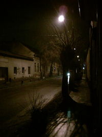 Illuminated street amidst buildings at night