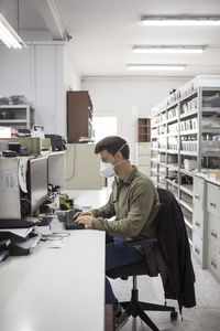 Man wearing mask working on computer at table