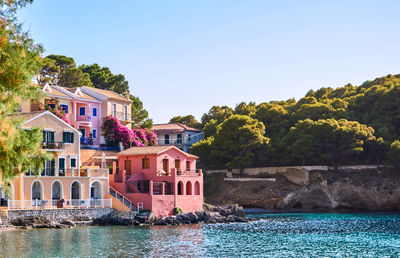 Houses by building against clear sky