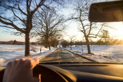 Cropped image of car on snow covered field against sky