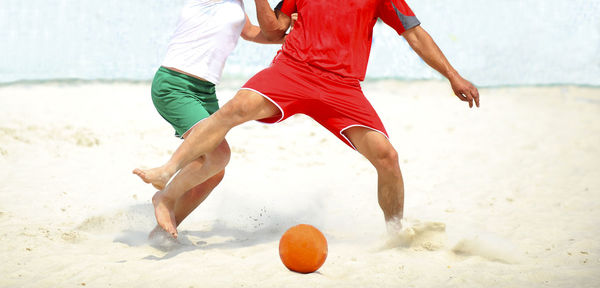 Low section of people with ball on sand at beach