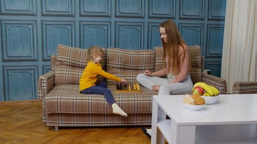 Rear view of woman sitting on sofa at home