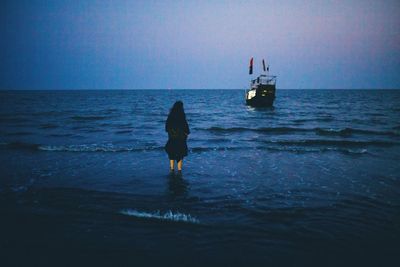 Rear view of silhouette boat in sea against clear sky