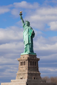 Low angle view of statue of liberty against cloudy sky