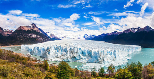 Scenic view of iceberg and mountains against sky