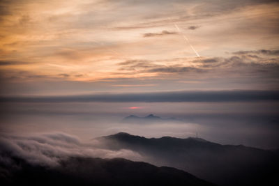 Scenic view of cloudscape covering mountains against sky during sunset