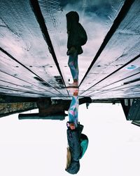 Upside down image of girl standing on jetty against clear sky