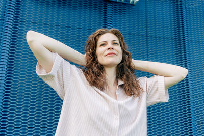 Portrait of young woman standing against blue sky