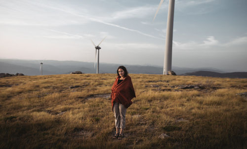 Full length portrait of young woman standing on field