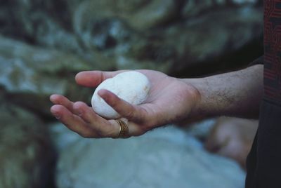 Cropped image of man holding rock outdoors