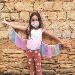 Portrait of happy girl standing against stone wall