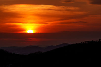 Scenic view of silhouette mountains against orange sky