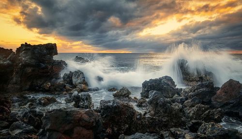 Scenic view of waterfall against sky during sunset