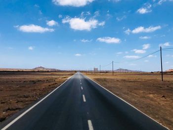 Road passing through land against sky