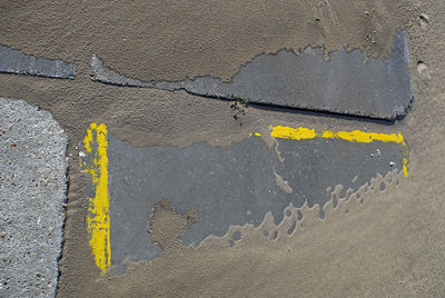 High angle view of yellow arrow symbol on road