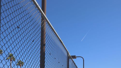 Low angle view of fence against clear blue sky