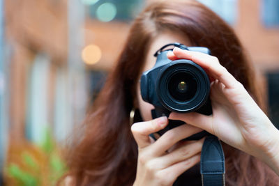 Portrait of woman photographing with camera in city