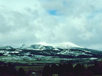 Scenic view of snow covered mountains against cloudy sky