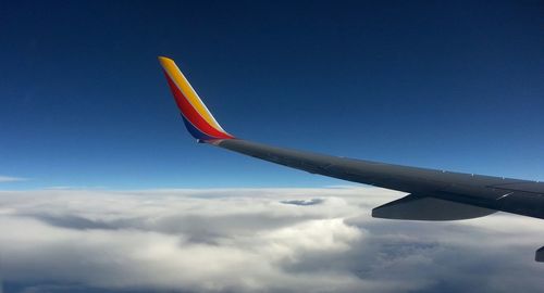 Low angle view of airplane wing against cloudy sky