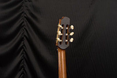 Cropped image of acoustic guitar on bed