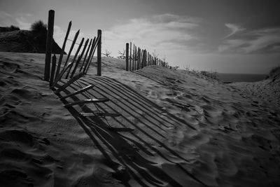 Wooden posts on beach against sky