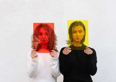 Portrait of lesbian couple standing against white wall