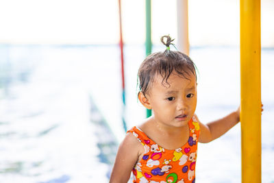 Cute girl standing by swimming pool in water park