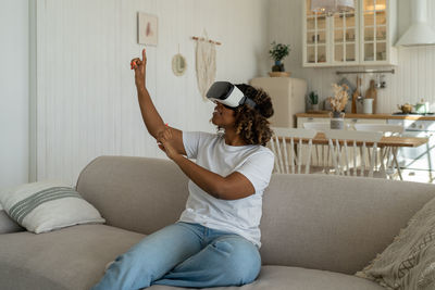 Young woman using phone while sitting on sofa at home